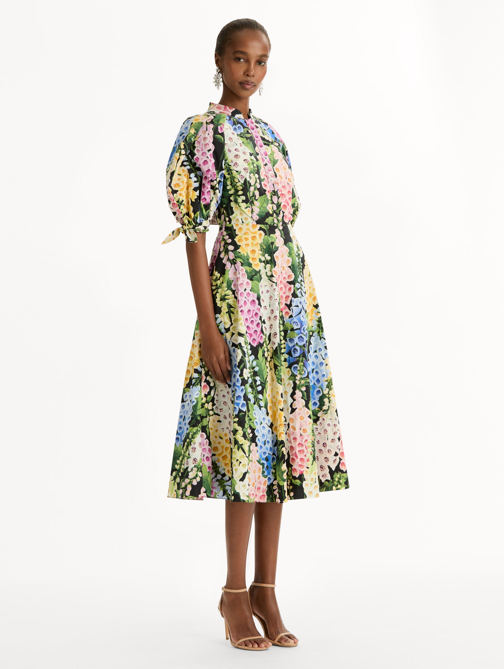 Black floral Foxglove Cotton Poplin Puff Sleeve Dress with voluminous elbow-length puff sleeves, a fitted waist, and a flared skirt that falls below the knee. Side View.
