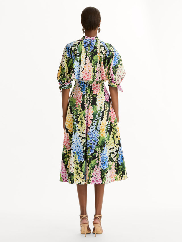 Black floral Foxglove Cotton Poplin Puff Sleeve Dress with voluminous elbow-length puff sleeves, a fitted waist, and a flared skirt that falls below the knee. Back View.