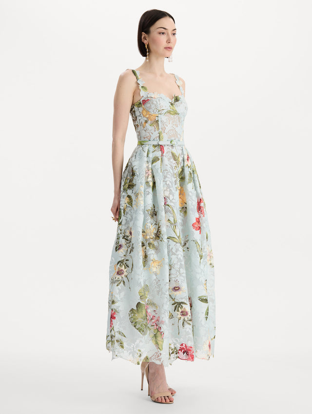 The model is wearing the Dominican Mixed-Floral Guipure Cocktail Dress in Saltwater Blue. Featuring floral detailing on straps, sweetheart neckline, structured bodice, and full skirt. Side View.