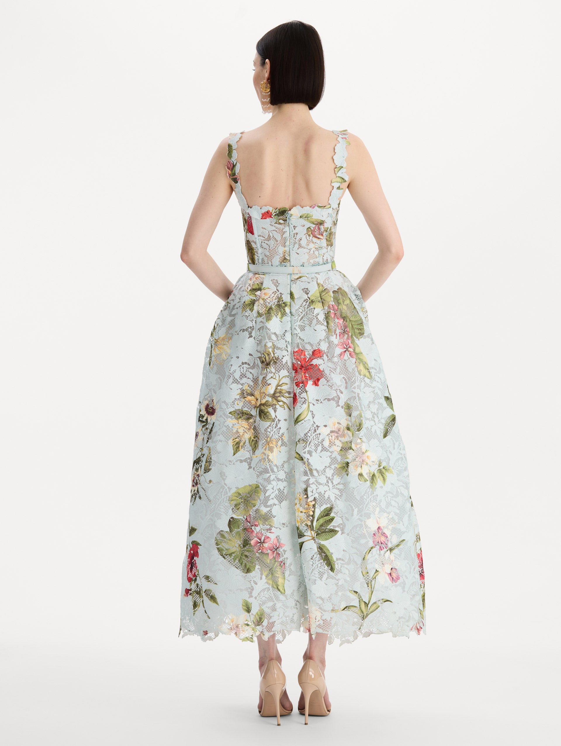 The model is wearing the Dominican Mixed-Floral Guipure Cocktail Dress in Saltwater Blue. Featuring floral detailing on straps, sweetheart neckline, structured bodice, and full skirt. Back View.