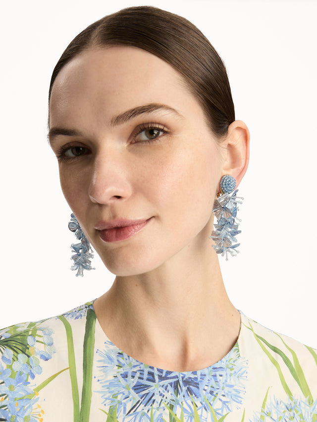 Blue Sequin Tassel Clip-On Earrings featuring layered translucent petals cascading from a round woven stud. Front View.