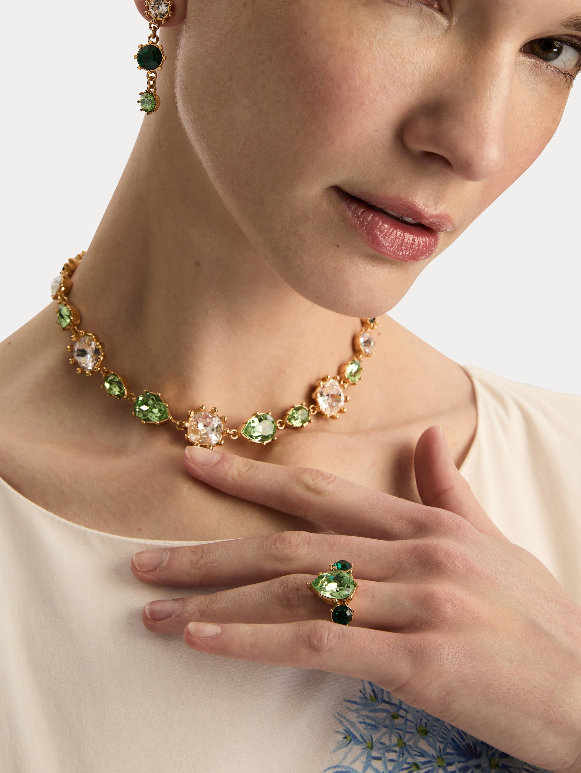Gold Faceted Crystal Ring featuring a central pear-shaped green gemstone flanked by two round emerald-green stones. Front View.