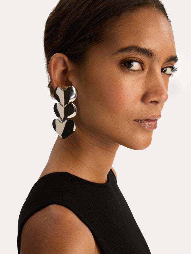 Silver Heart Drop Clip-On Earrings featuring a vertical stack of three hearts. Side View. 