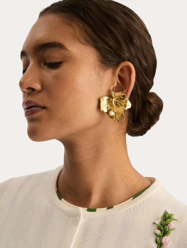 Gold Ivy Leaf Earrings featuring a textured finish and accented with a single small pearl at the base. Side View.
