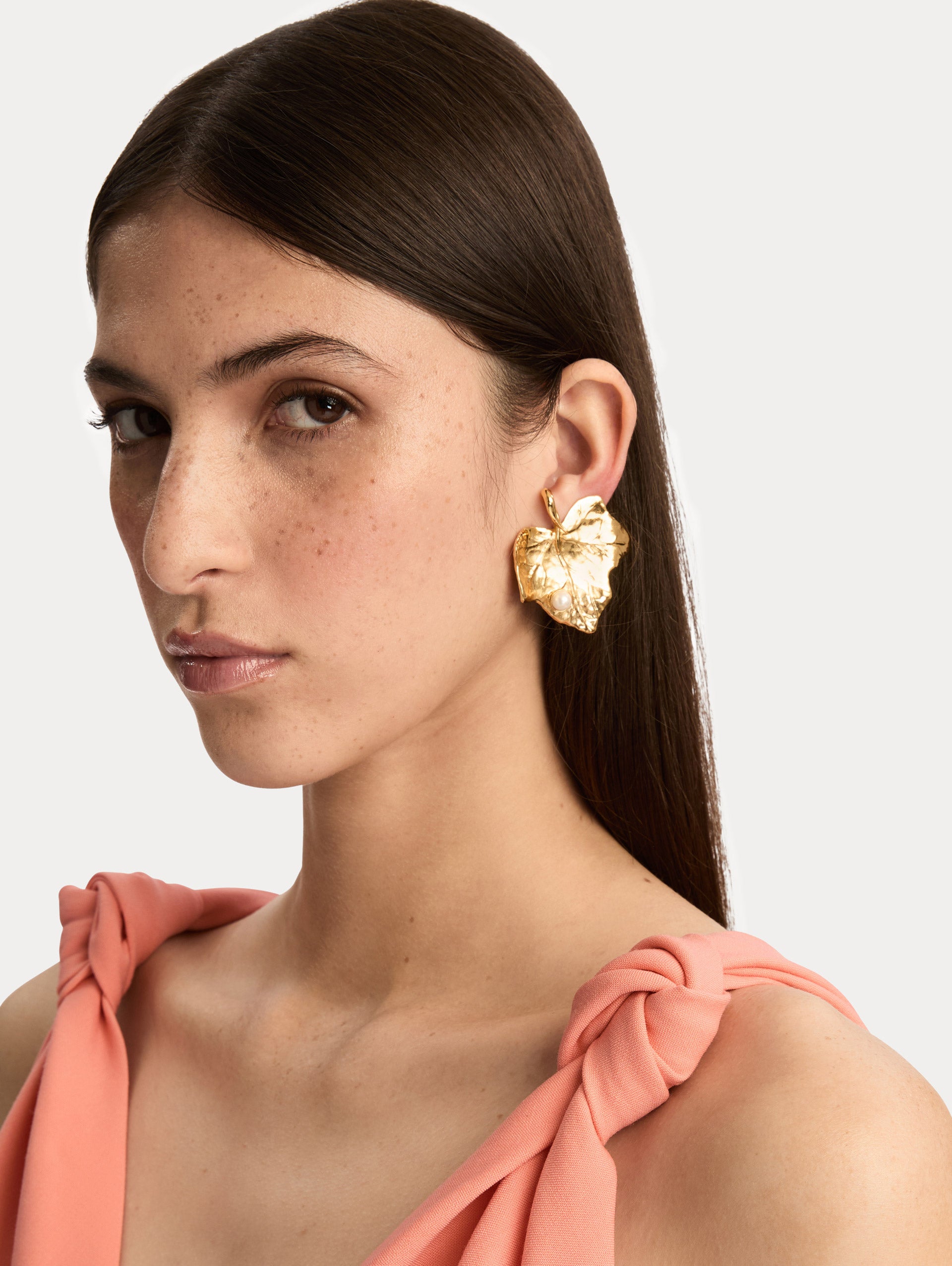 Gold Ivy Leaf Earrings featuring a textured finish and accented with a single small pearl at the base. Side View.