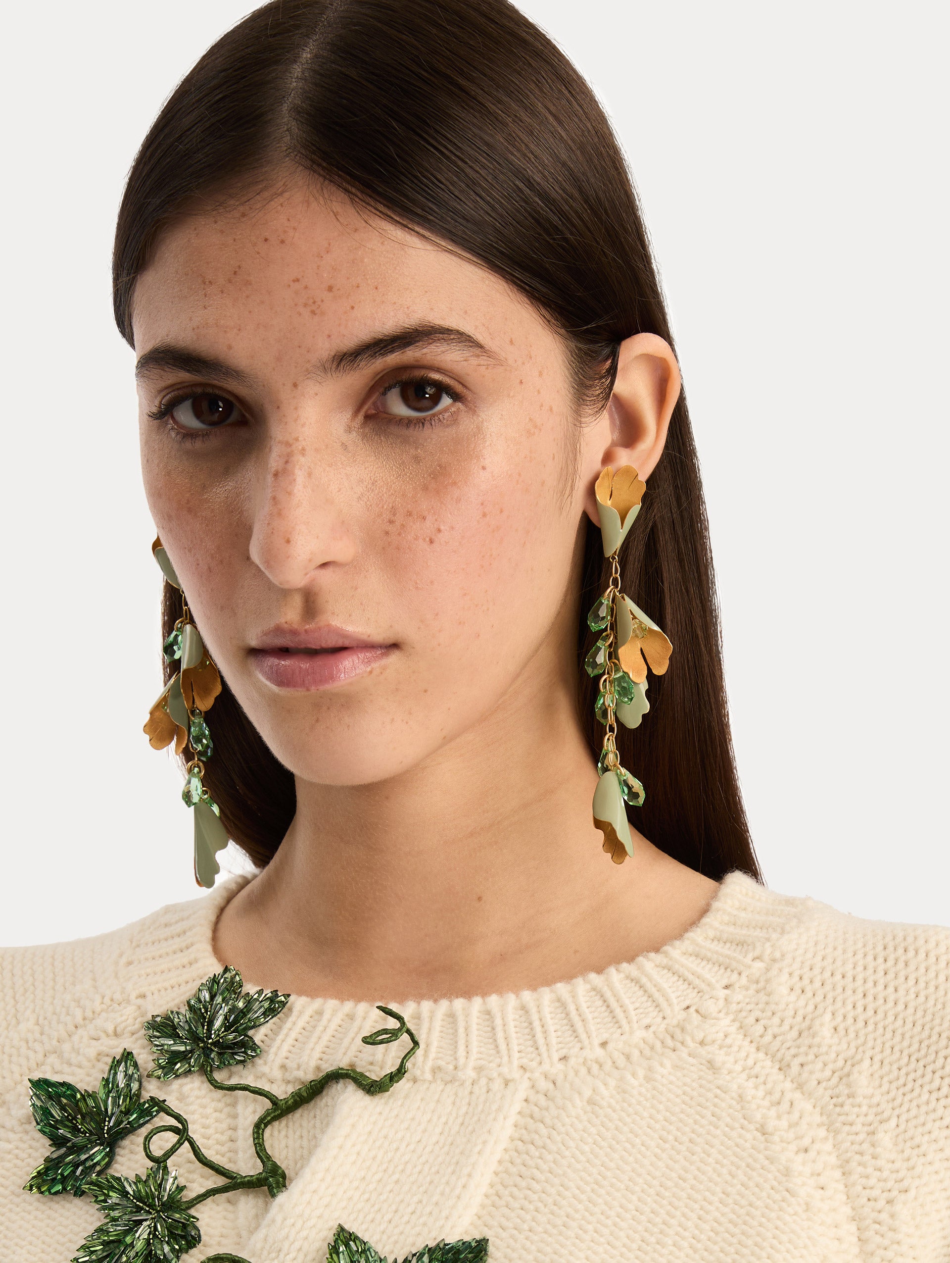 Gold and green Bellflower Drop Earrings featuring layered petal motifs with emerald crystal accents. Front View.