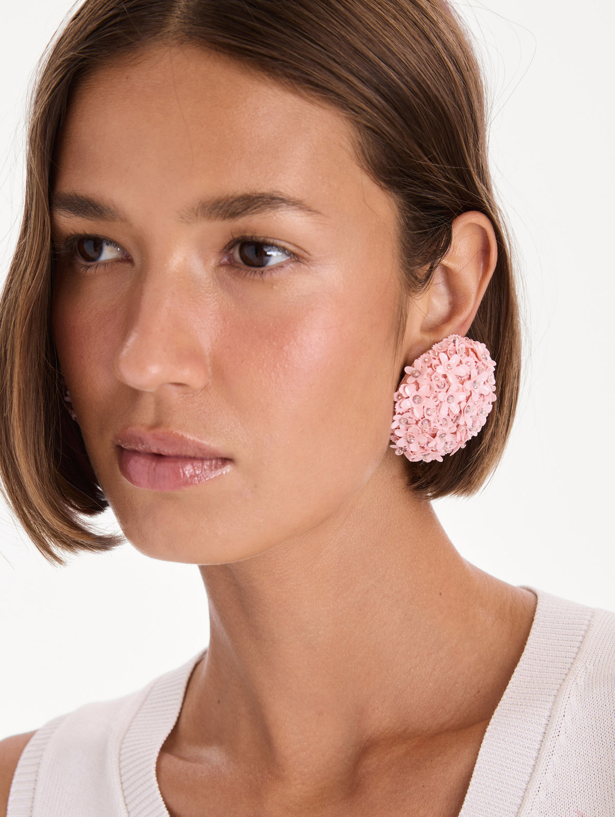 The model is wearing flower pompom large earrings. Front view.
