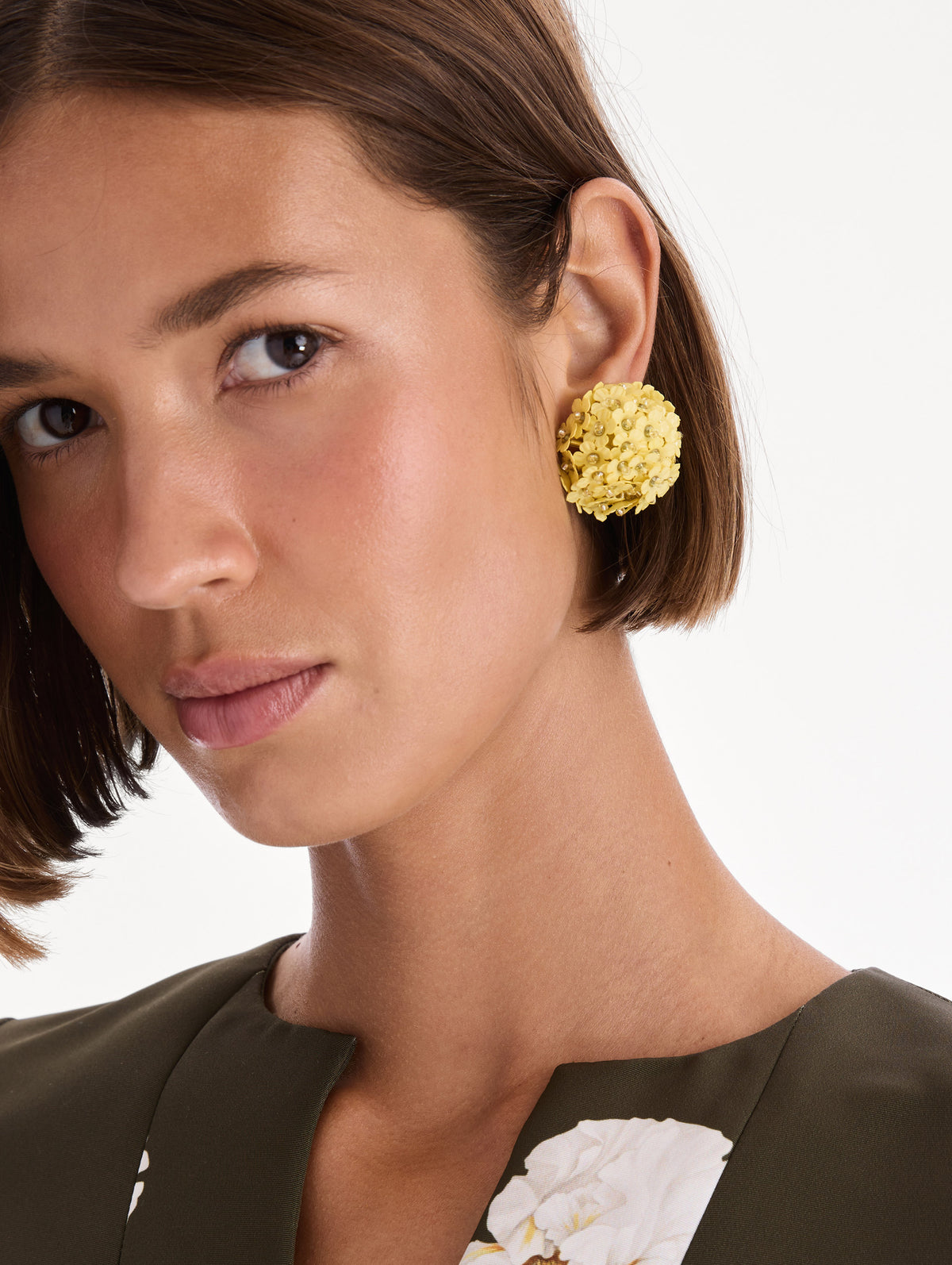 The model is wearing flower pompom small earrings. Front view.