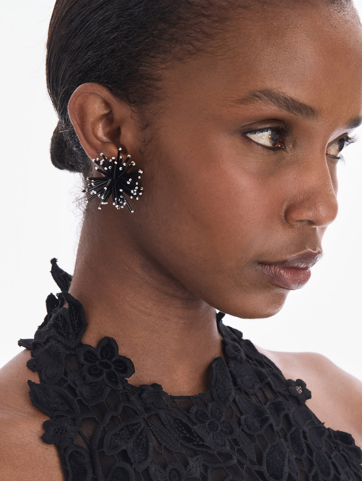 The model is wearing bugle bead firework stud earrings. Front view.