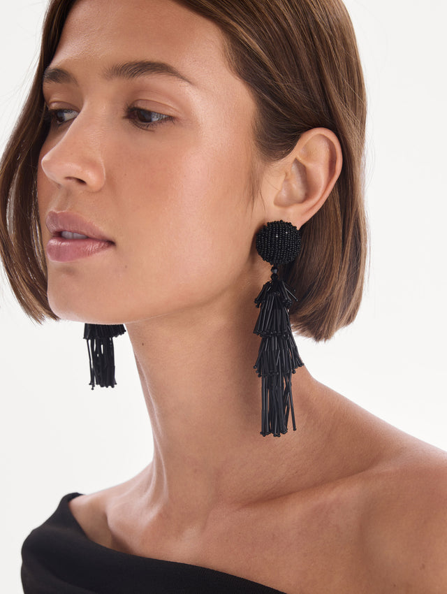 The model is wearing fringe tassel earrings. Front view.