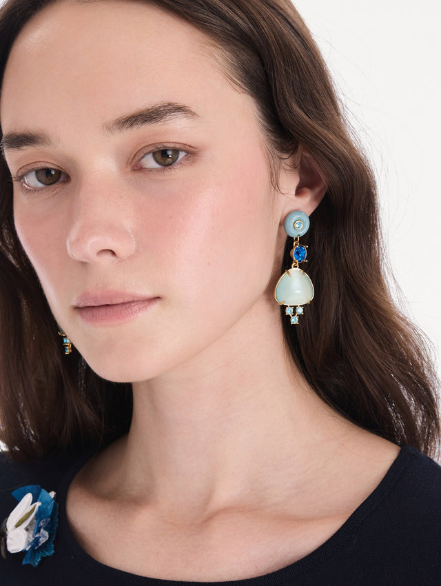 The model is wearing cabochon drop crystal earrings. Front view.