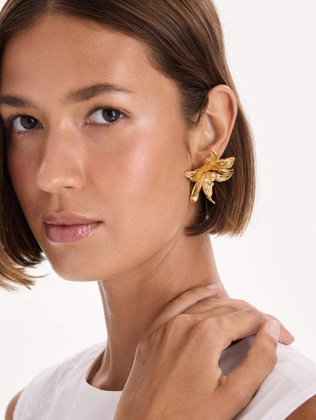 The model is wearing lily flower earrings. Front view.
