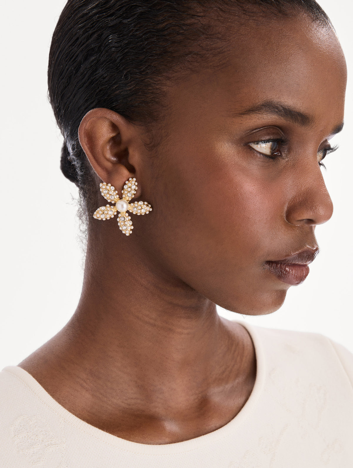 The model is wearing large pearl flower earrings. Front view.