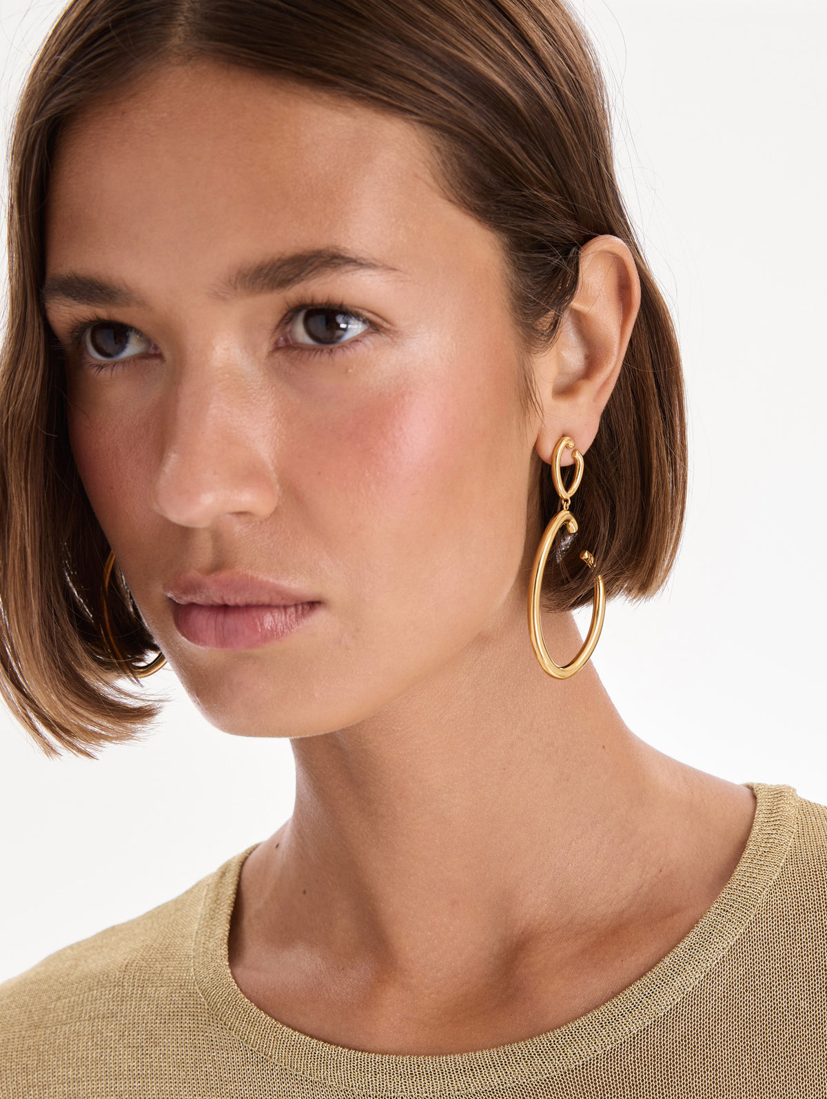 The model is wearing large O logo earrings. Front view.