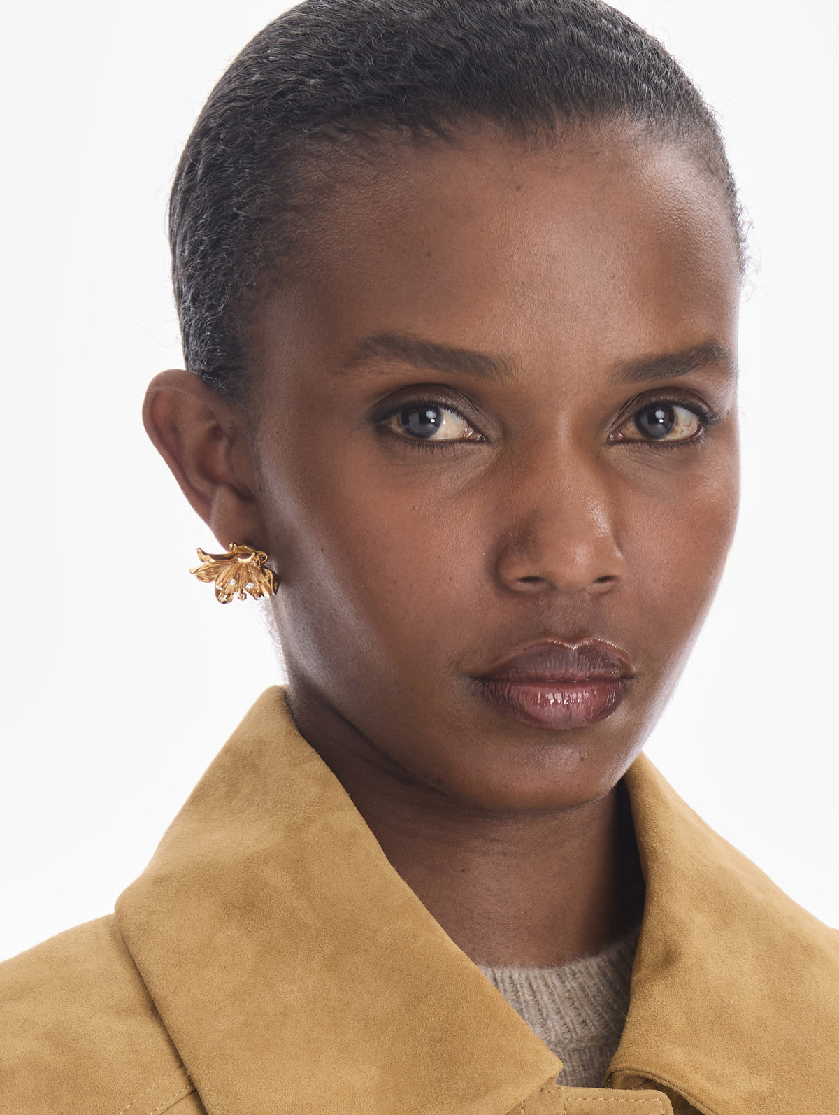 The model is wearing small lily flower earrings. Front view.