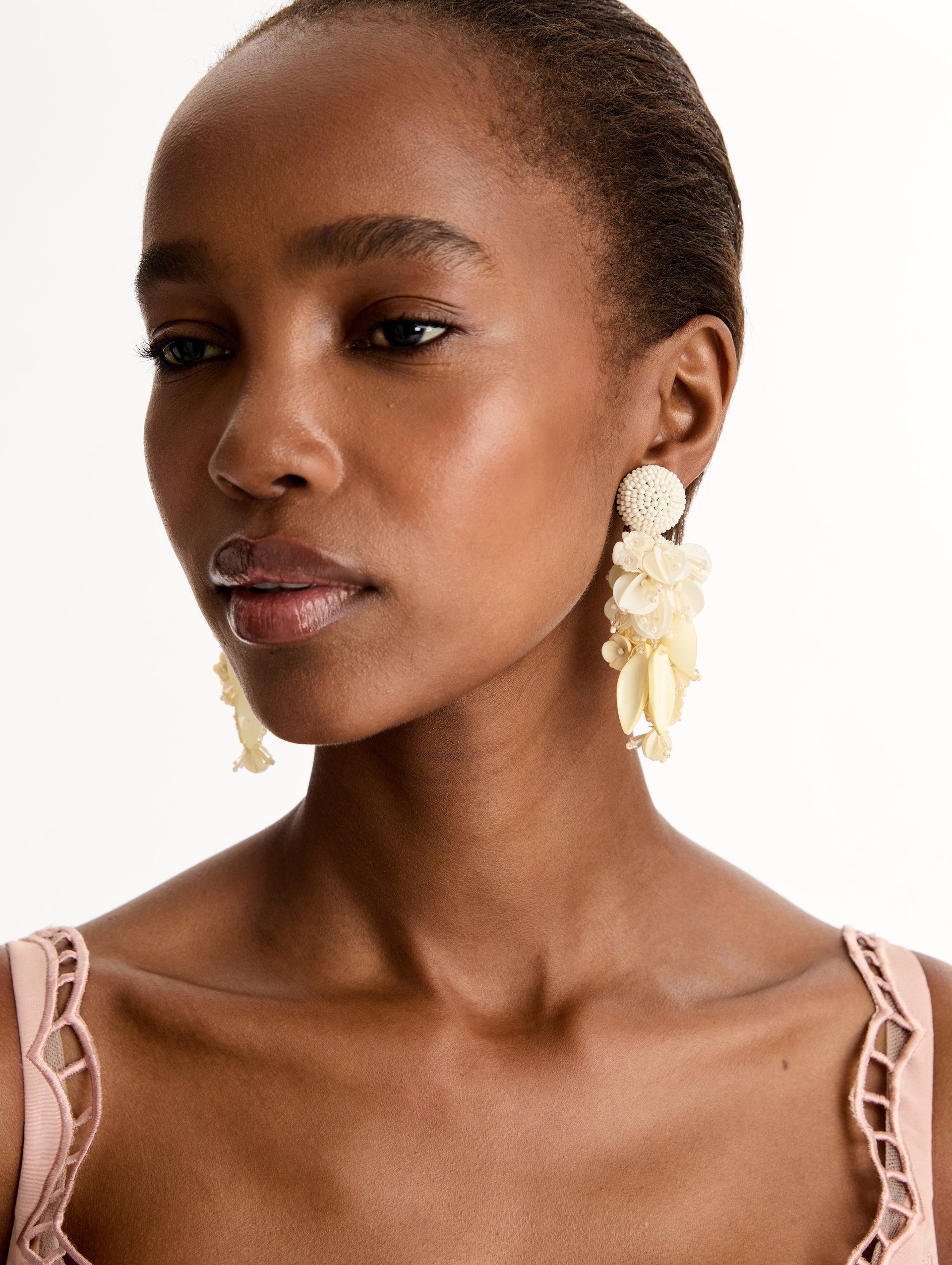 White Cascading Petal Drop Clip-On Earrings featuring a round beaded stud at the lobe with cascading clusters of glossy pink petals, beads, and floral-shaped components. Front View.