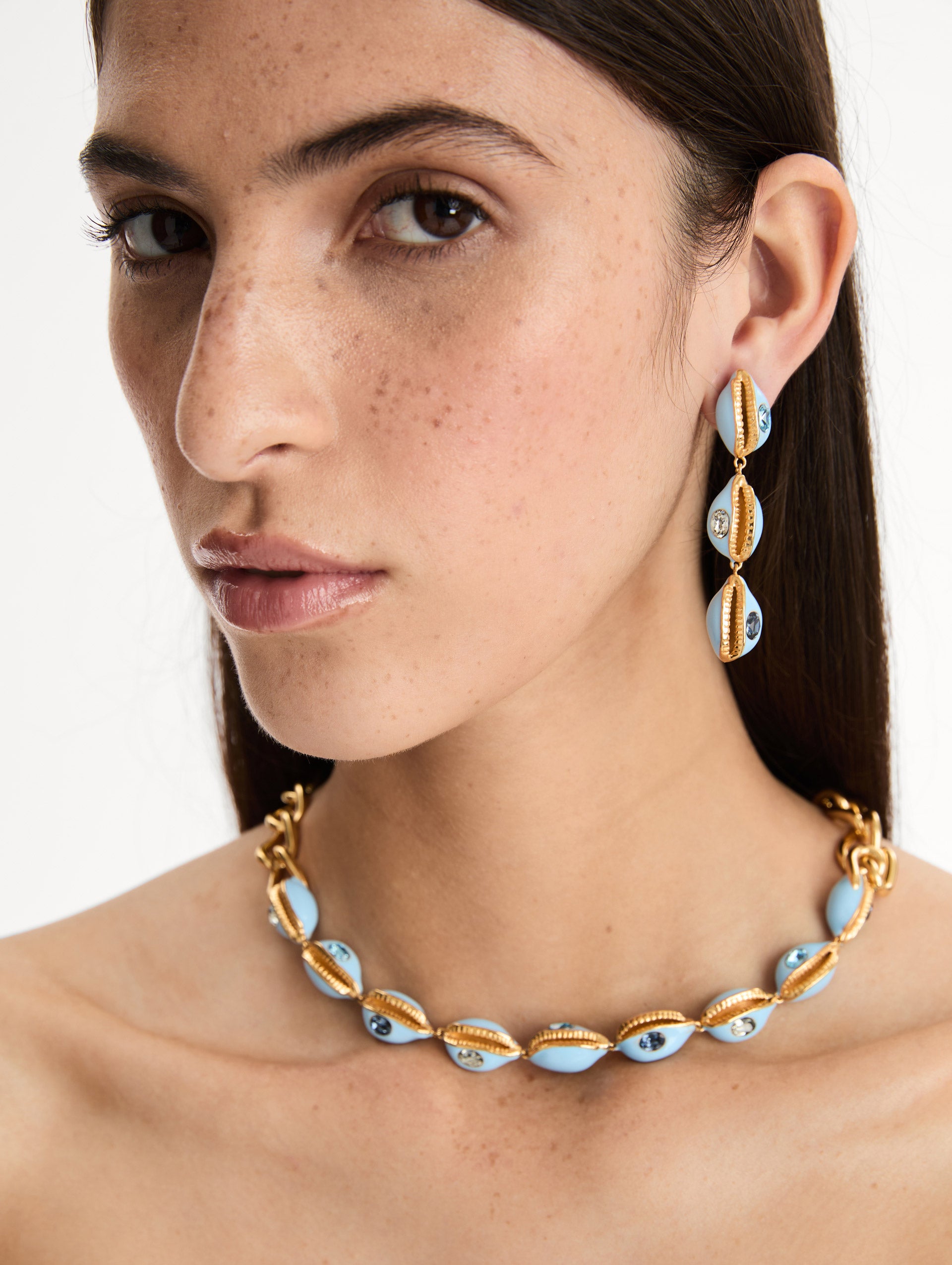 Gold and blue Cowrie Shell Drop Clip-On Earrings featuring stacked shell motifs with crystal accents. Side View.