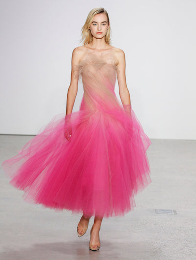 The model walks the runway in an ombré semi-sheer tulle cocktail dress where shades of nude transition to bright pink.