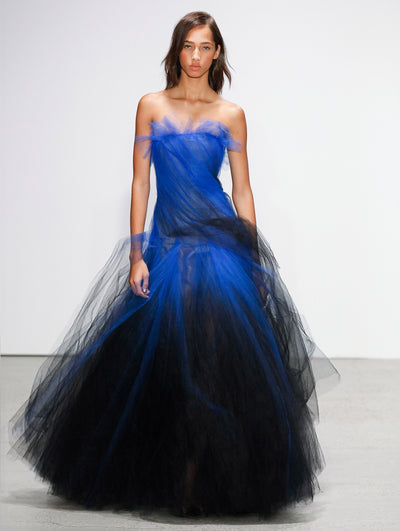 The model walks the runway in an ombré semi-sheer tulle evening gown where shades of bright blue transition to black.