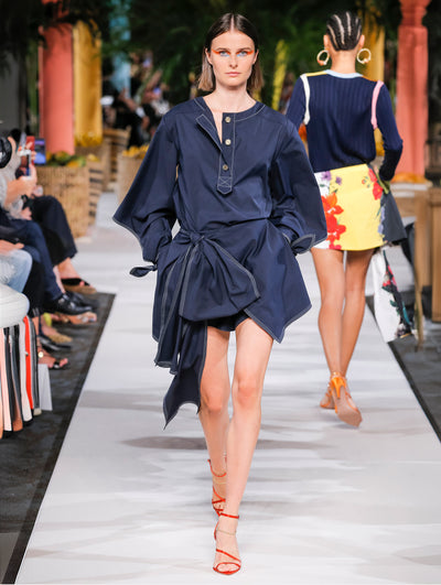 A model wears a black dress with bow belt