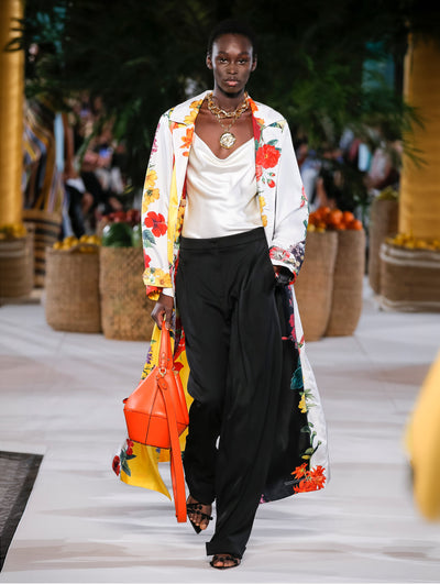 A model wears black pants and white silk top with multicolor flower printed coat