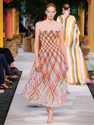 Model wears strapless dress with multicolor woven strands.