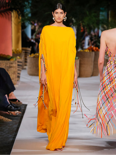 A model wears a yellow caftan with rainbow strings