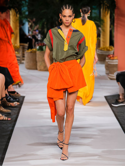 A model wears orange shorts and a green yellow orange top