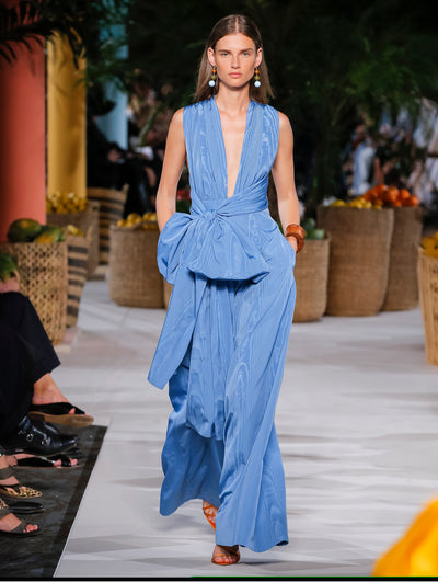 A model wears a blue gown with a low slit in the middle chest