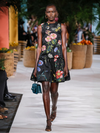A model wears a black cocktail dress with colorful printed flowers