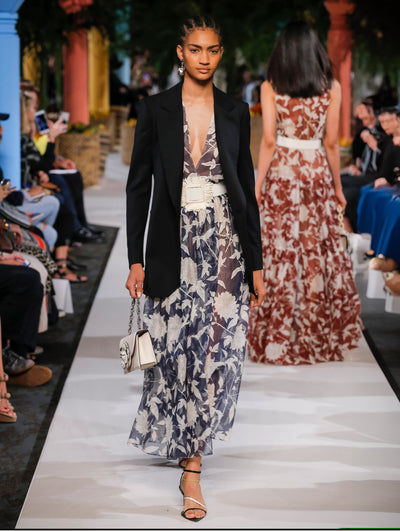 A model wears a black blazer and black and white flower printed see thru dress