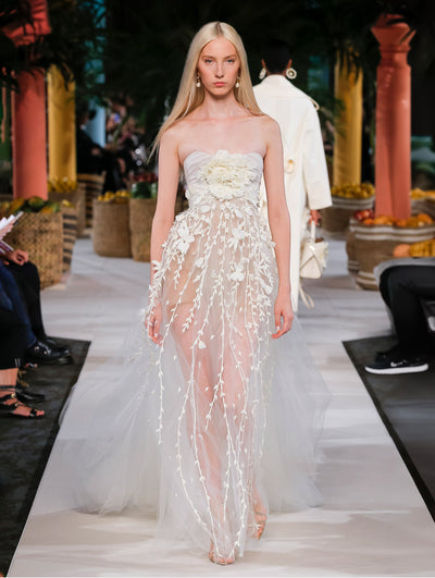 A model wears a white gown with flower and vine embroidery