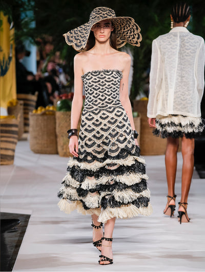 A model wears a black and nude raffia dress with matching sun hat