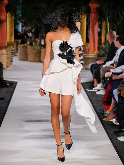 A model wears white shorts and top with black embroidered flower and black top