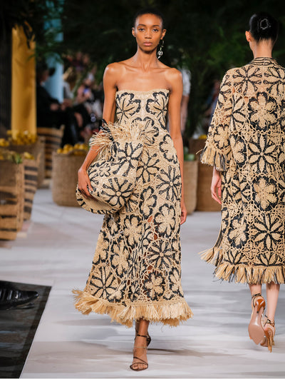 A model wears a black and nude raffia dress and matching bag