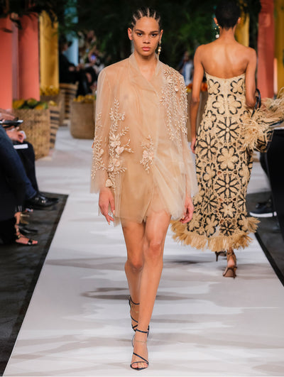 A model wears a nude tulle coat with flower embroidery
