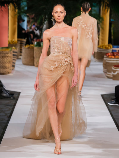 A model wears a nude dress with a bustier and flowers embroidered