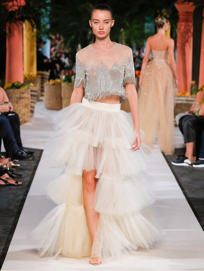 A model wears a white tulle skirt and crystal top